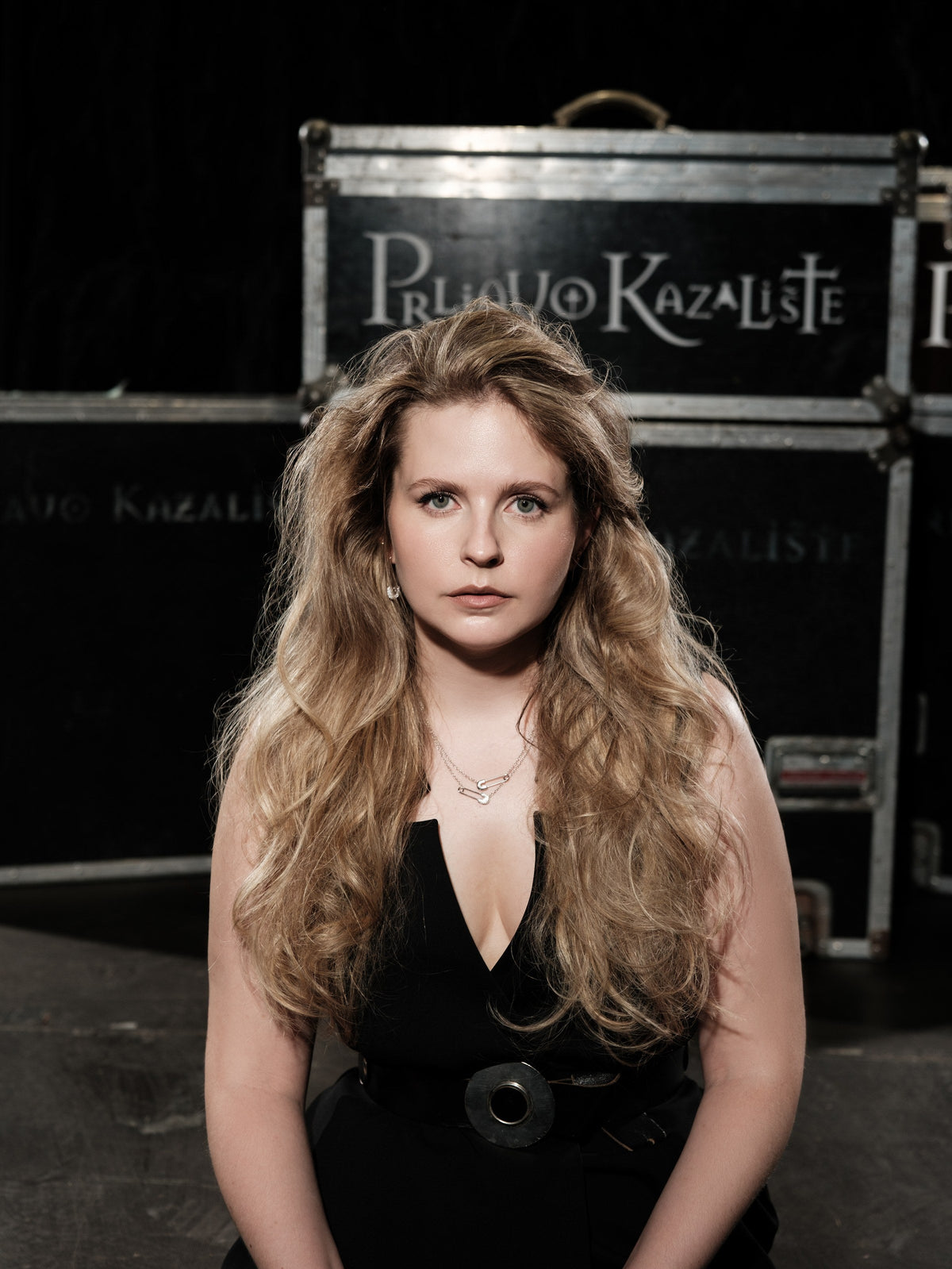 Woman in a black dress in front of stage flight cases