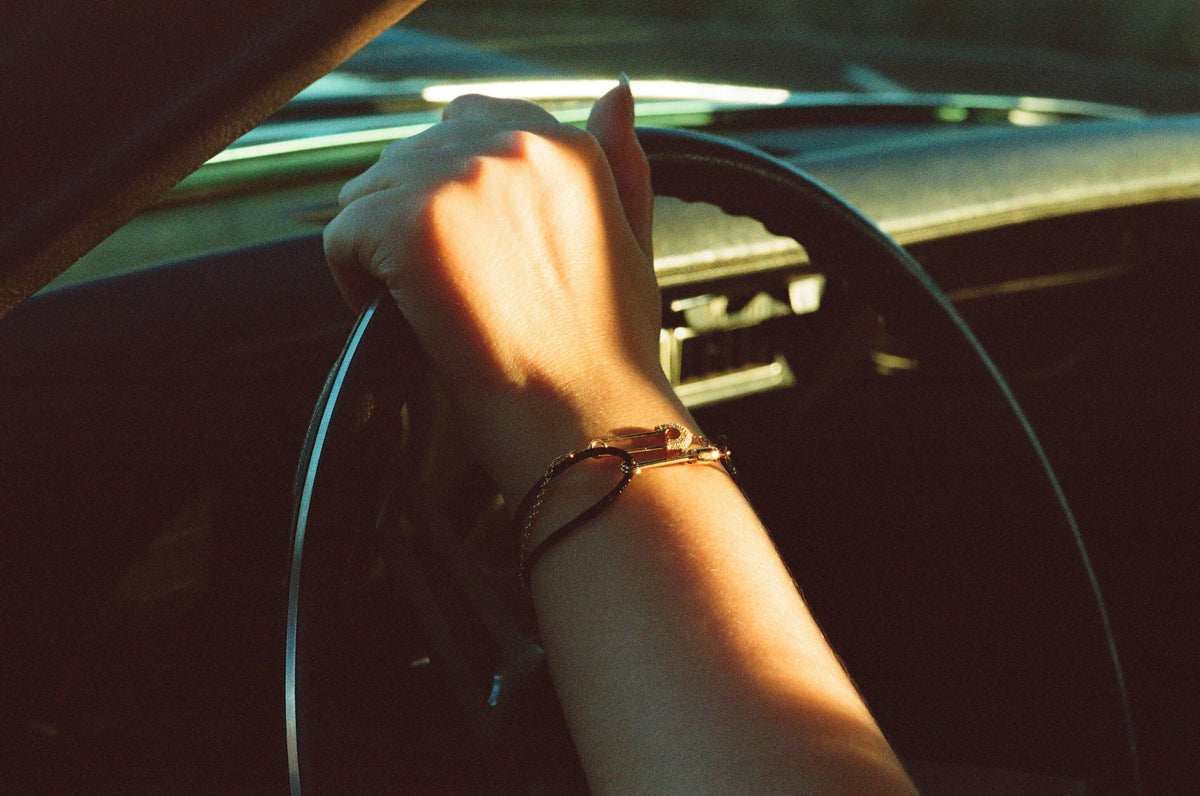 449 safety pin bracelet on a wrist, hand on a steering wheel